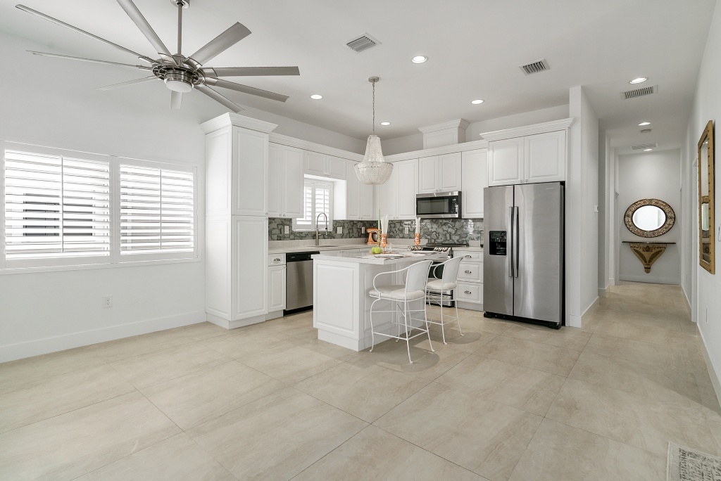 Minimalist White Kitchen with Marble Backsplash Chandelier and Stainless Appliances.jpg